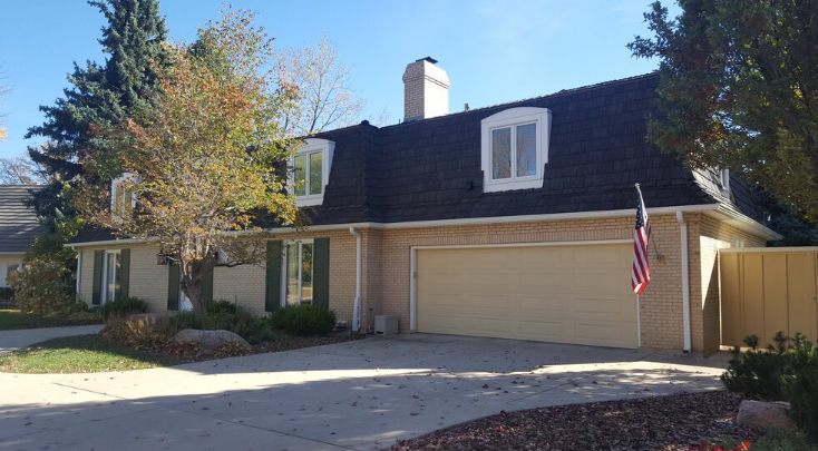Brick home with dark cedar shake roof and attached garage.