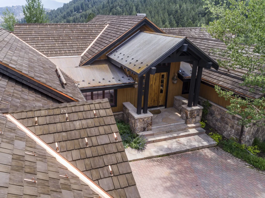 Mountain home with synthetic cedar shake roof and metal entry canopy.