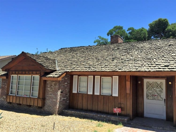 Weathered cedar shake roof on wood-sided home (before replacement).