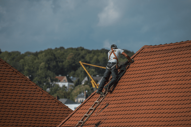 A worker replacing broken tiles on a roof. 