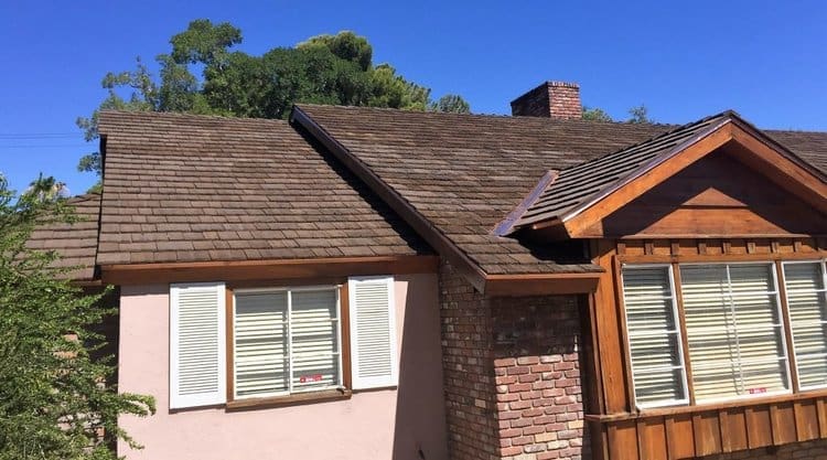 Weathered cedar shake roof on wood-sided home (after replacement).