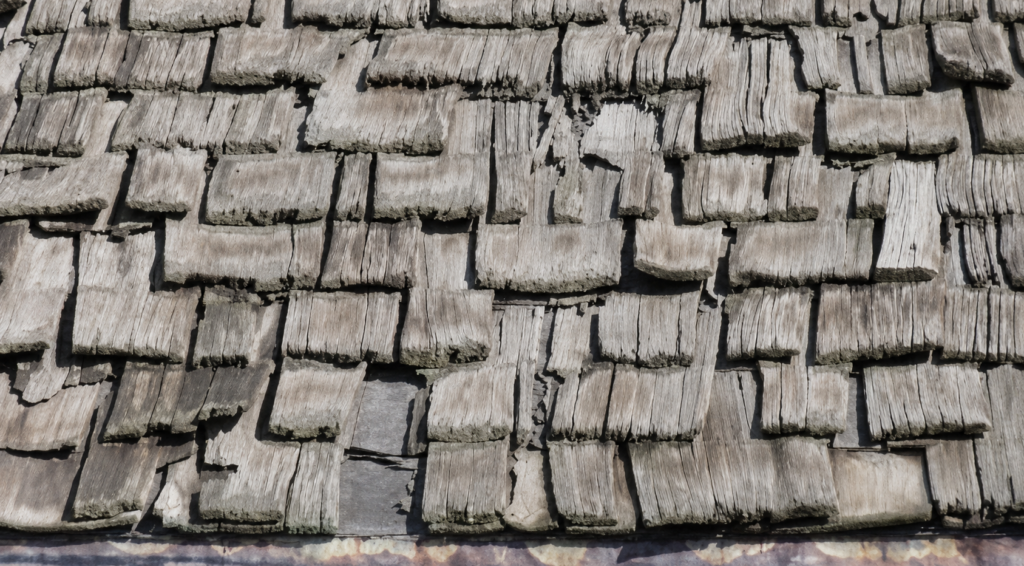 Worn cedar shake roof with missing and damaged shingles.