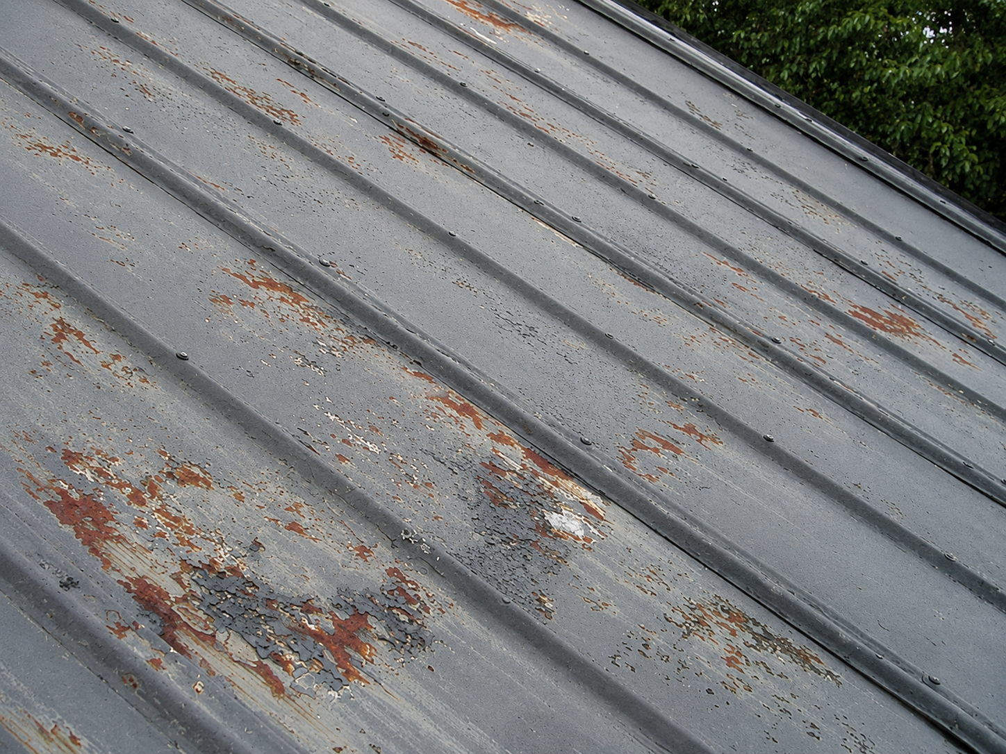 Weathered metal roof with peeling paint and surface rust.