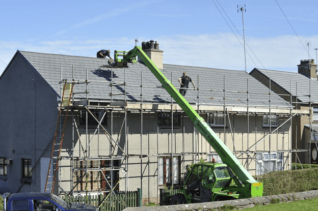 Roof replacement project with workers on scaffolding.