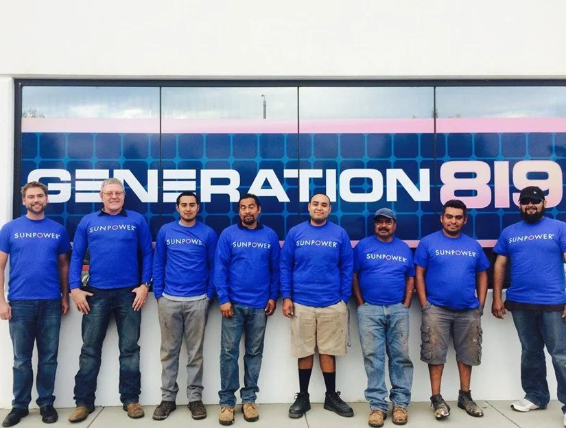 A team of solar energy professionals standing in front of a Generation 819 sign.