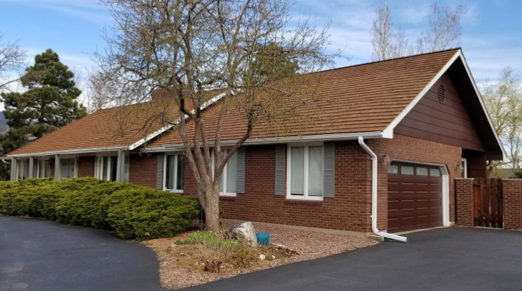 Brick home with golden cedar shake roof.