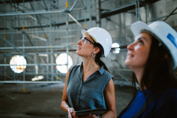 Two women in construction hats inspecting construction. 