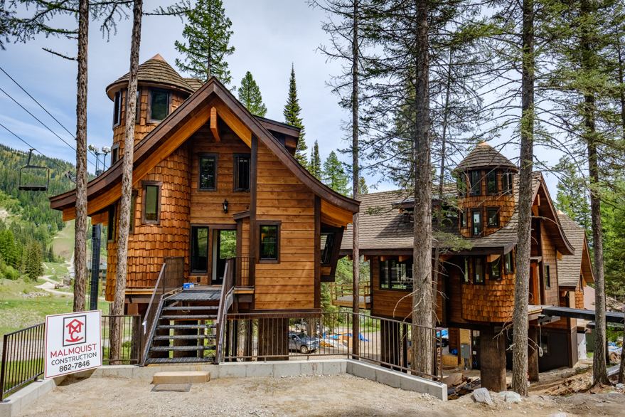Mountain home with golden cedar shakes, curved rooflines, and turret-style towers.