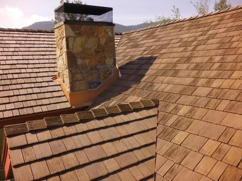 Close-up of a CeDUR synthetic shingle roof with a stone chimney.