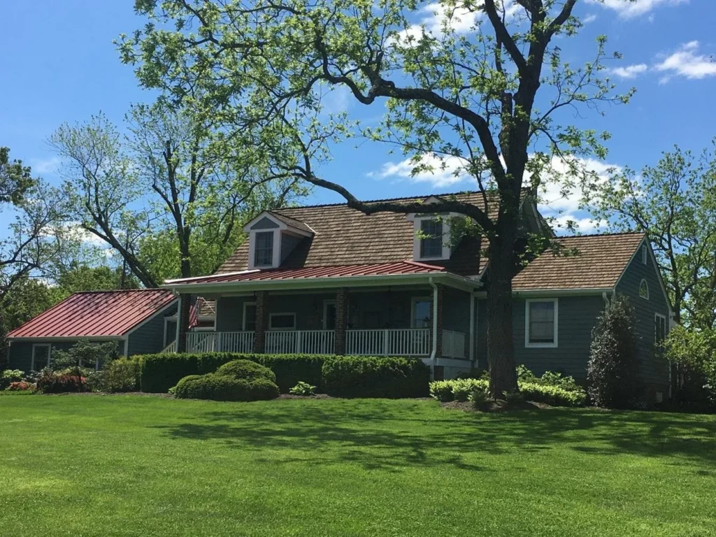 An image of a countryside home with pitched roof and dormers, set on a grassy lawn.