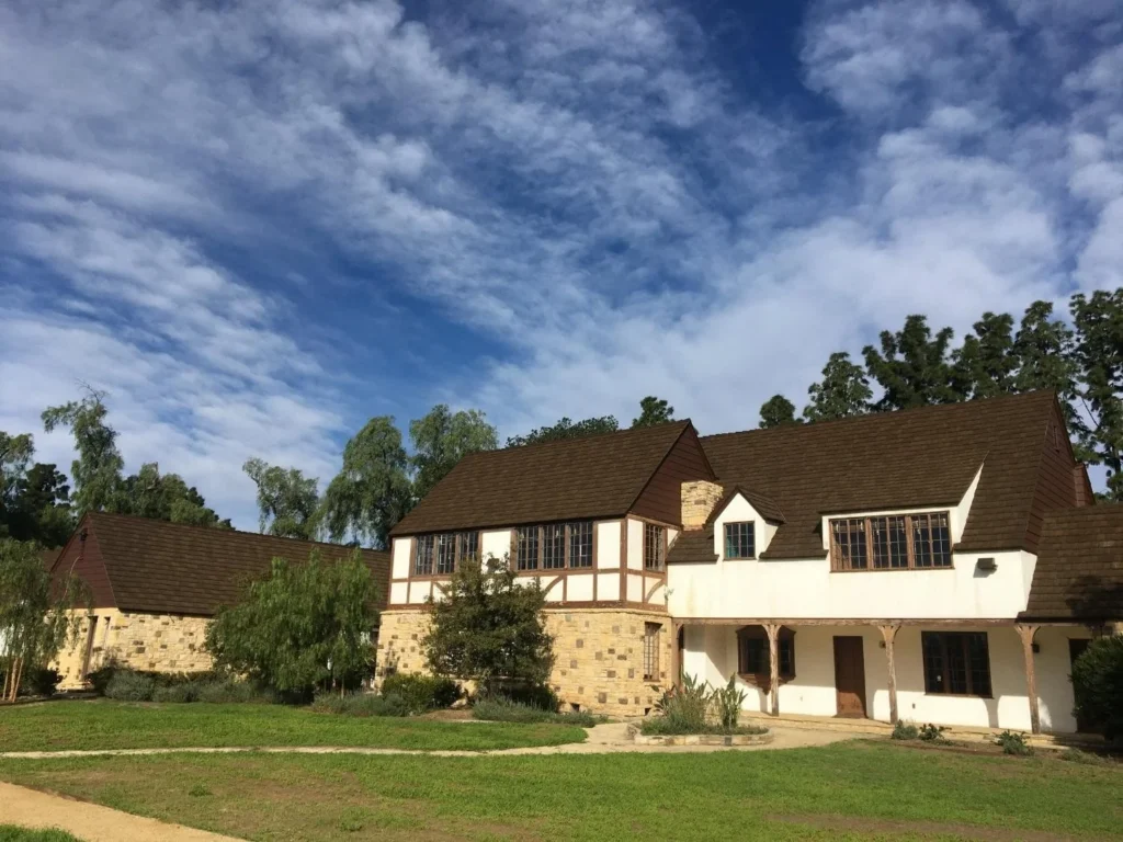 Tudor-style home with steep CEDUR shake roofs, stone and stucco exterior.
