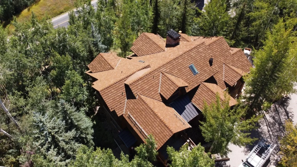 Aerial view of a home with a cedar-style shake roof surrounded by trees.