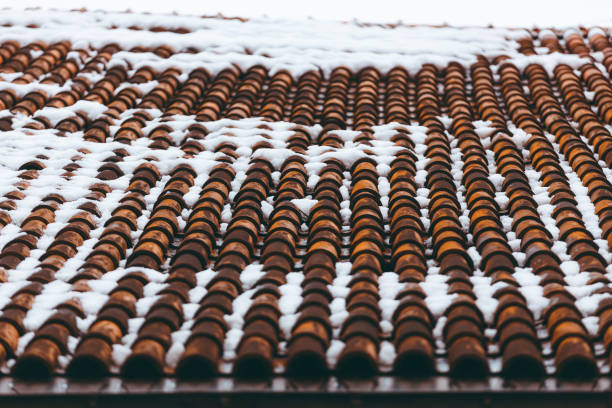 Clay tile roof partially covered with melting snow.