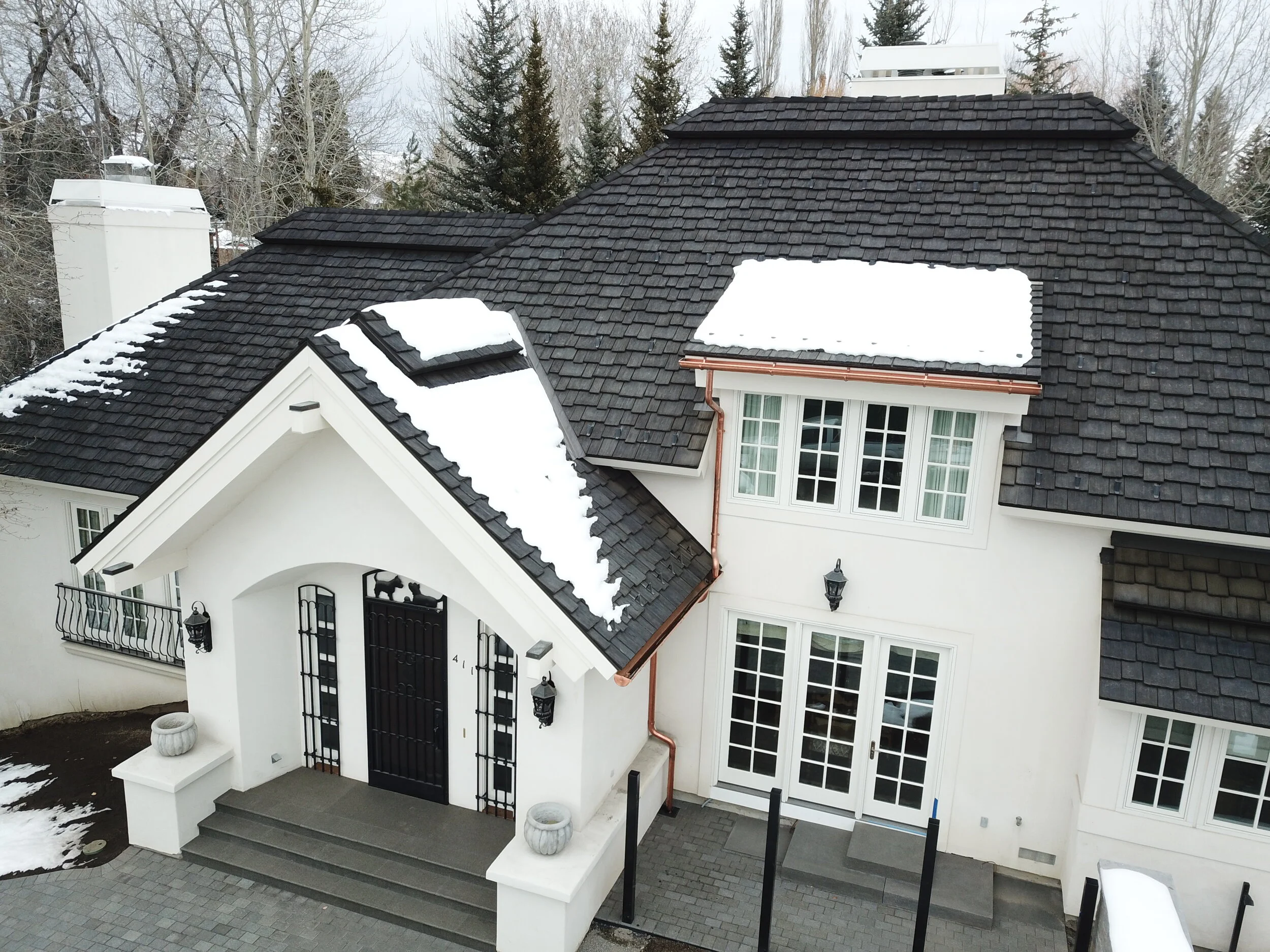 A dark shake roof on a white home.