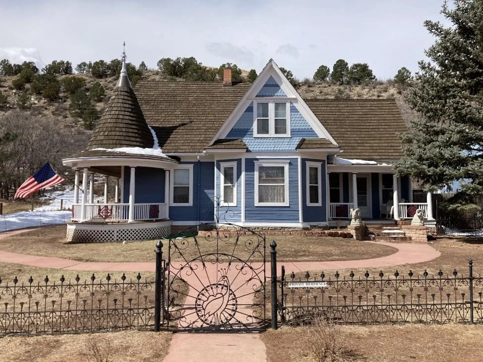 Victorian-style blue home with cedar shake roof and wraparound porch.