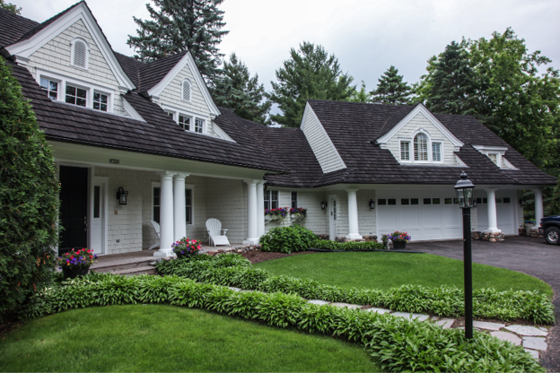 CEDUR Shiloh roof on a white Minnesota home with lush landscaping, installed by  Kuhl’s Contracting.
