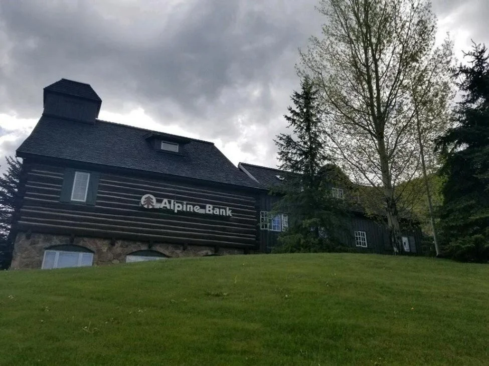 Alpine Bank building with log-style and stone siding, located on a hill, featuring CEDUR Walden synthetic shake roofing.
