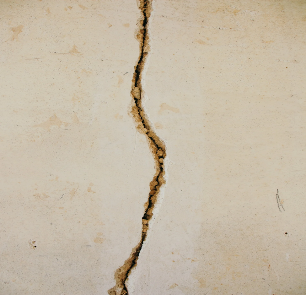 Close-up of a deep crack running through a concrete surface.