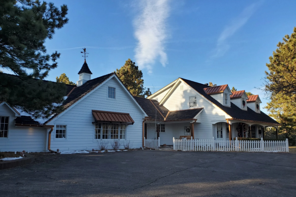 White farmhouse with gable roof and composite shake roofing.