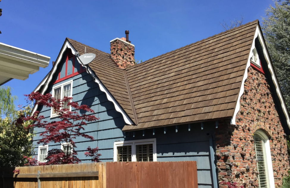 Gable roof home with composite shake roofing and brick chimney.