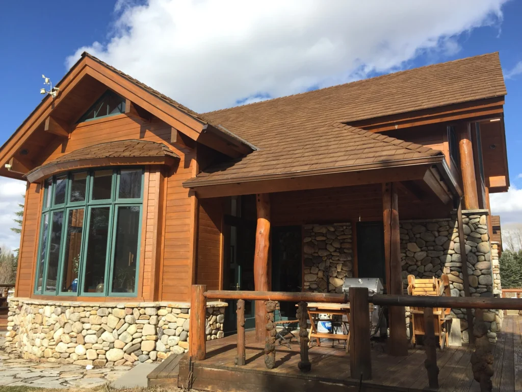 A rustic home exterior with green window trim.